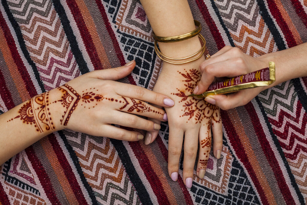 Mehendi artist applying intricate henna design on bride’s hands